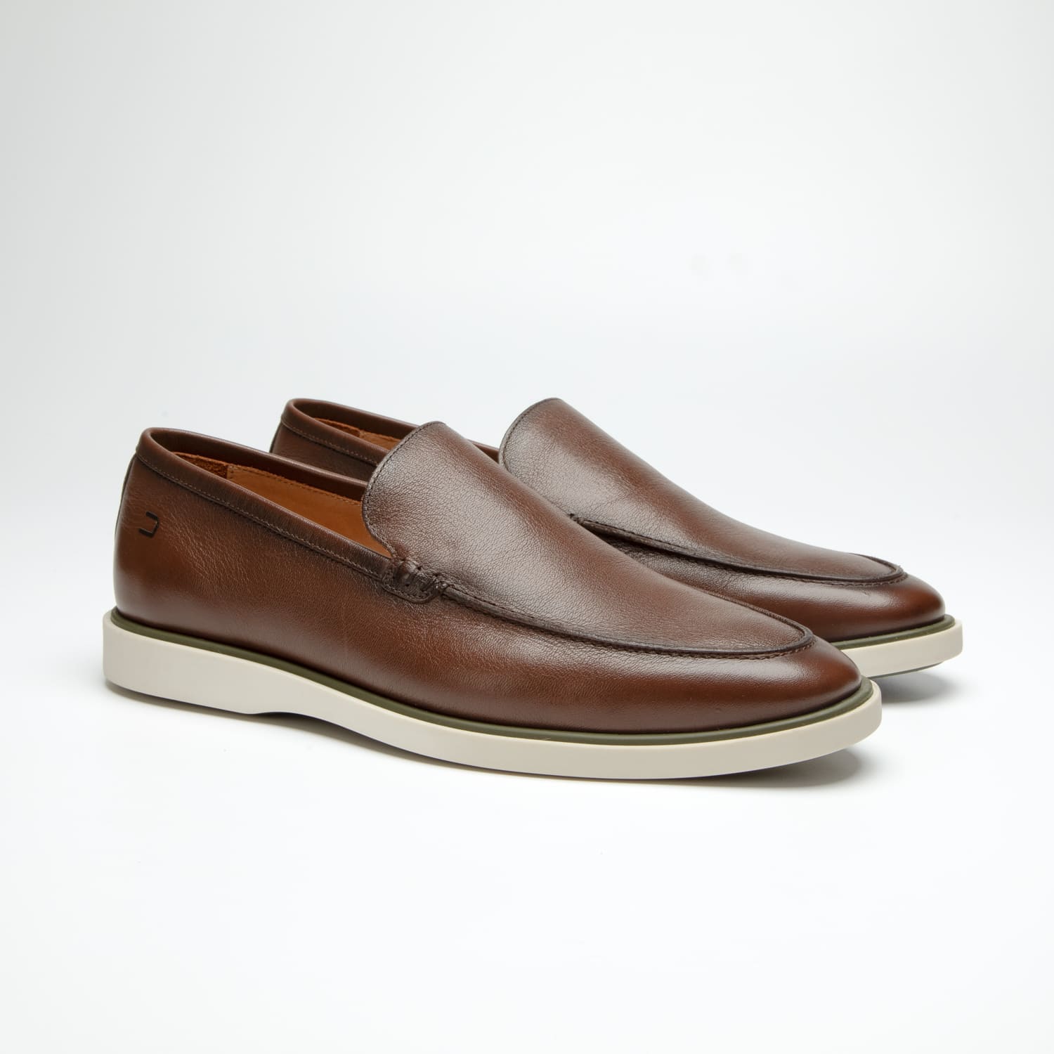 par de sapatos douss bourbon de couro marrom, sem cadarço modelo slip on, palmilha de couro marrom claro com a escrita douss e solado de borracha branca visto de lado na diagonal