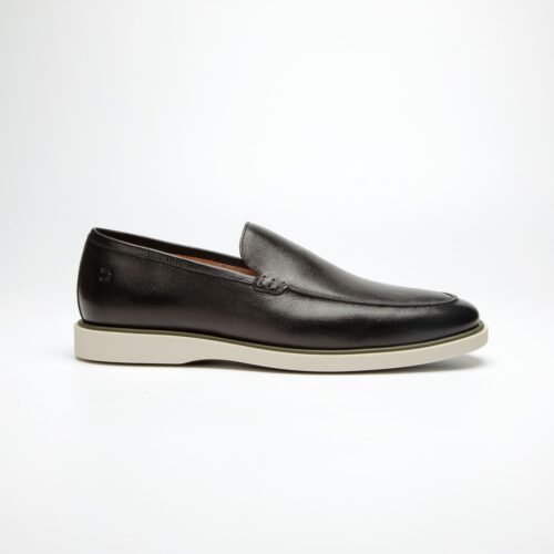 um pé de sapatos douss bourbon de couro preto, sem cadarço modelo slip on, palmilha de couro marrom claro com a escrita douss e solado de borracha branca visto de lado