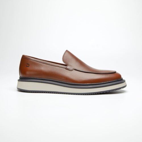 pé do sapato mocassim douss brooklin em couro marrom, sem cadarços, estilo slip on, com solado branco e preto, visto de lado