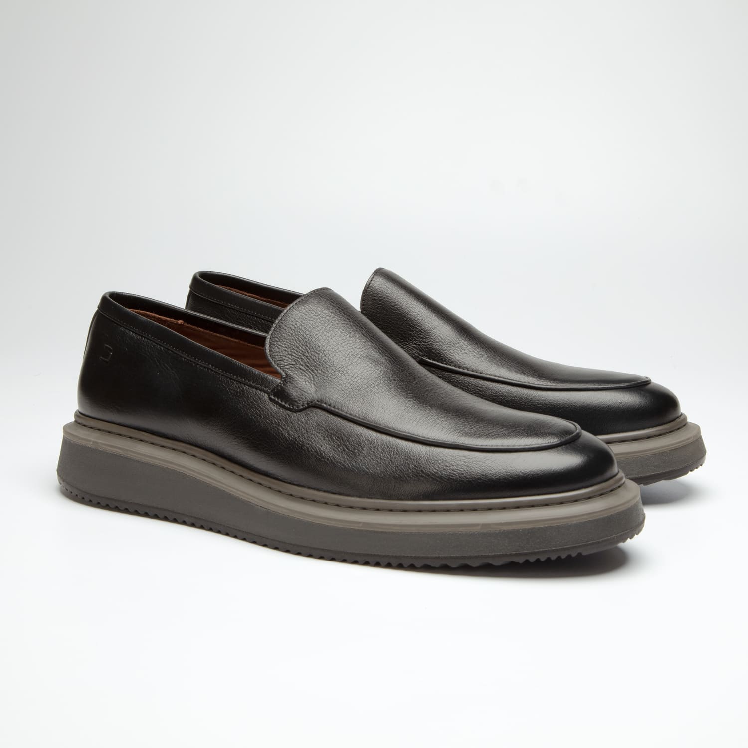 par do sapato mocassim douss brooklin em couro preto, sem cadarços, estilo slip on, com solado cinza escuro visto de frente na diagonal