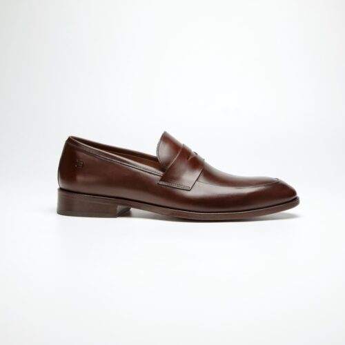 um pé do sapato social douss lucca estilo loafer, em couro marrom escuro, sem cadarços com a gravata na mesma cor, solado e salto na cor marrom escura visto de lado