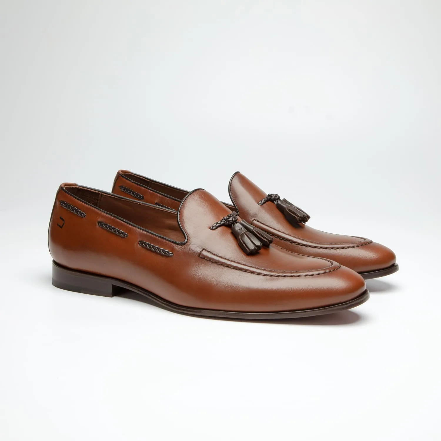 par de sapato douss veneto em couro marrom estilo mocassim com detalhes de cordão nas laterais na cor marrom e na parte da frente uma gravata bambolim e solado na cor marrom escura visto de frente na diagonal